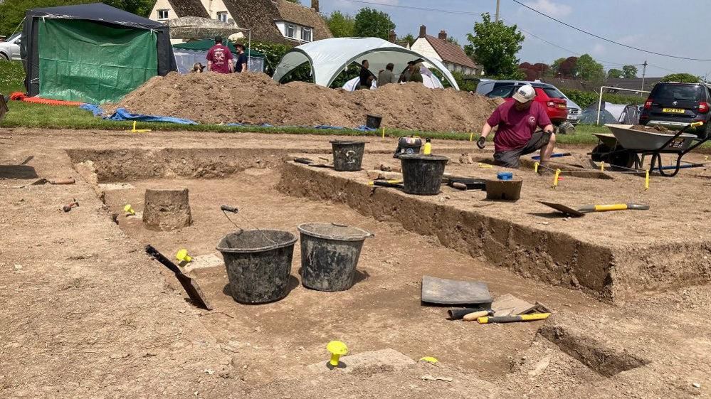An archaeological dig on a sunny day with buckets and tools