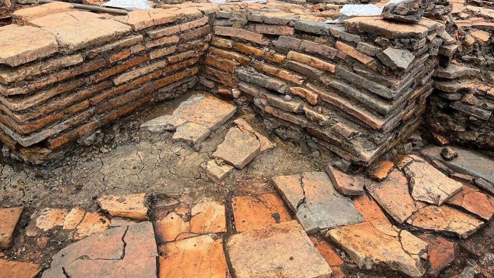 Part of a excavation with walls built from terracotta coloured tiles