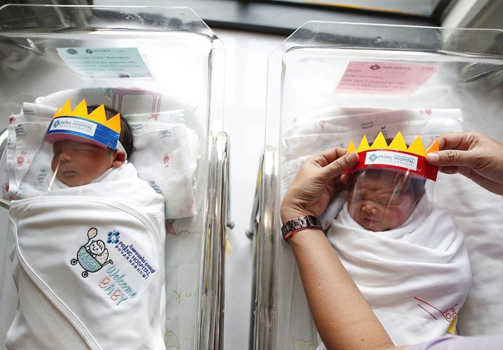 A nurse puts face shields on newborn babies at a hospital in Thailand