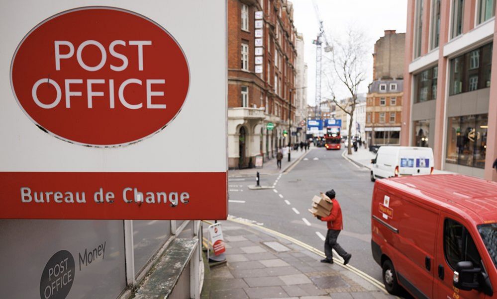 A post office worker carrying boxes from a red post office van into a post office branch in London on 8 January