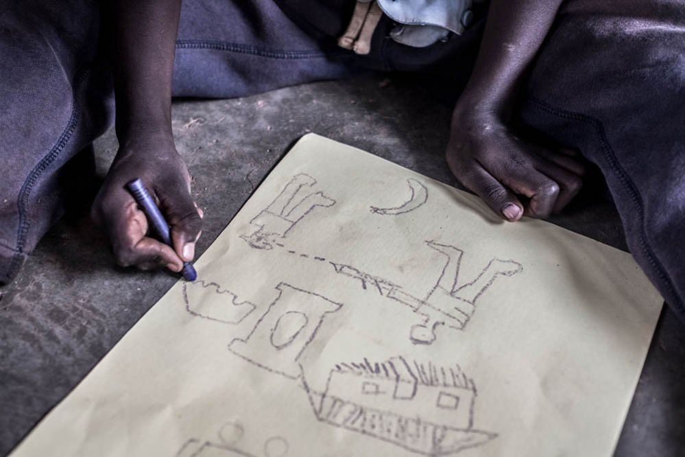 Richard, a young refugee from South Sudan, draws a picture of a violent scene