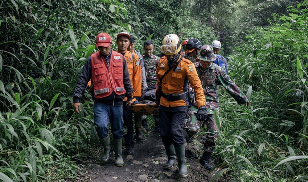 A group of rescue workers carrying a survivor amid foliage, in Agam West Sumatra on 4 December