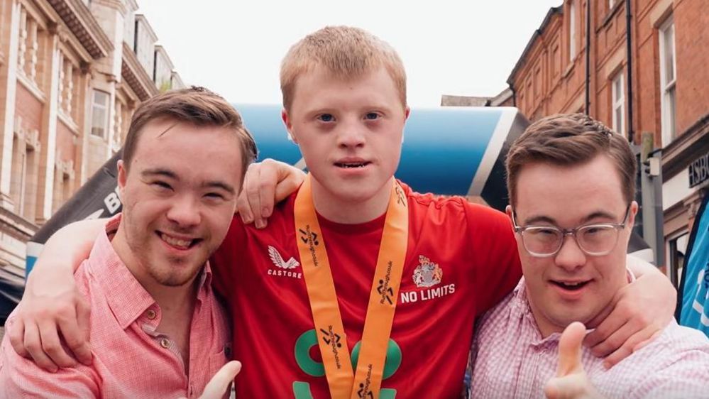 Joseph Adams flanked by his friends at the end of his final 10km race in Altrincham.