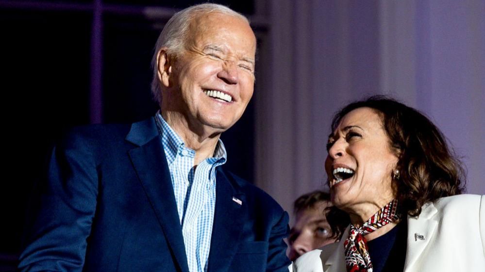 Joe Biden and Kamala Harris laughing, Biden has his eyes closed 