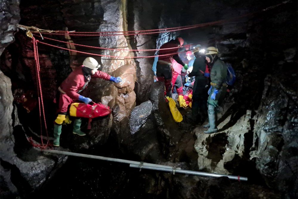 Rescue team carrying injured caver on a stretcher through a cave, 8 November 2021