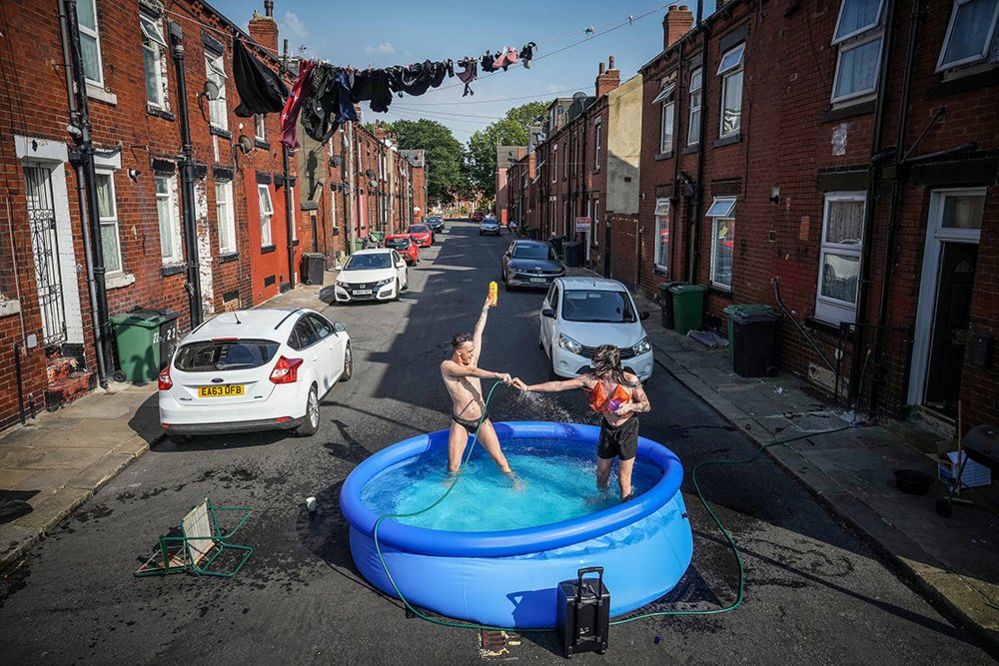 Residents take a dip in a paddling pool to cool off