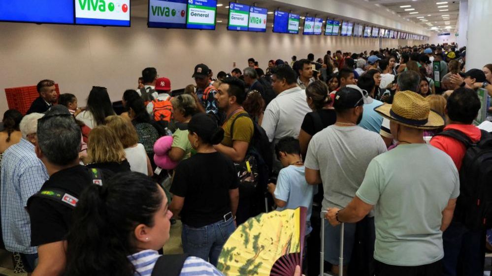 Passengers wait at the Cancun International Airport after a worldwide tech outage caused flight delays