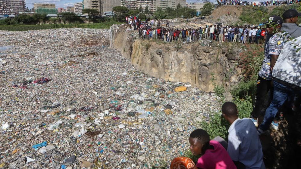 Crowds of people looking at a huge rubbish dump in Nairobi