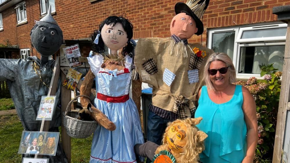 Nicky Sanders, standing by her Wizard of Oz scarecrows, Tin Man, Dorothy, Scarecrow and Lion