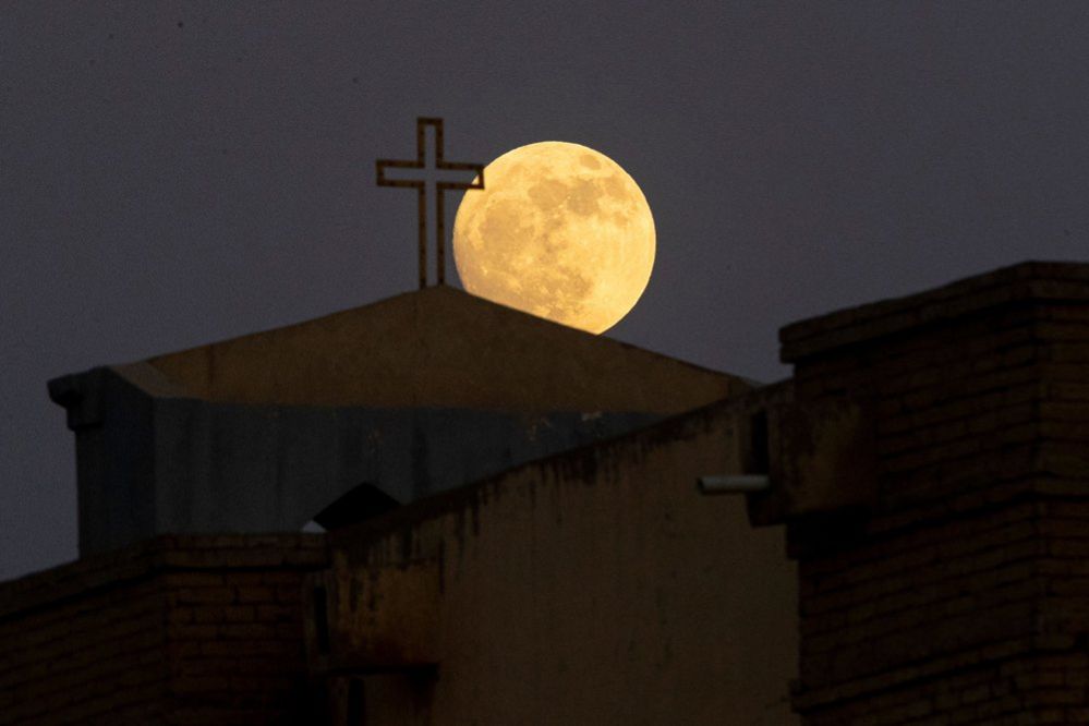 La luna si avvicina alla fine della sua fase di ceratura gibbosa mentre sorge sopra la Cattedrale della Vergine Maria Caldea nella città irachena di Bassora, il 2 luglio 2023