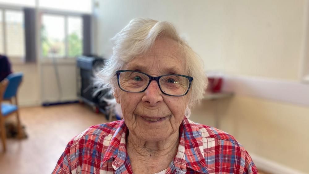 Kay Drinkwater with glasses, grey hair and red shirt