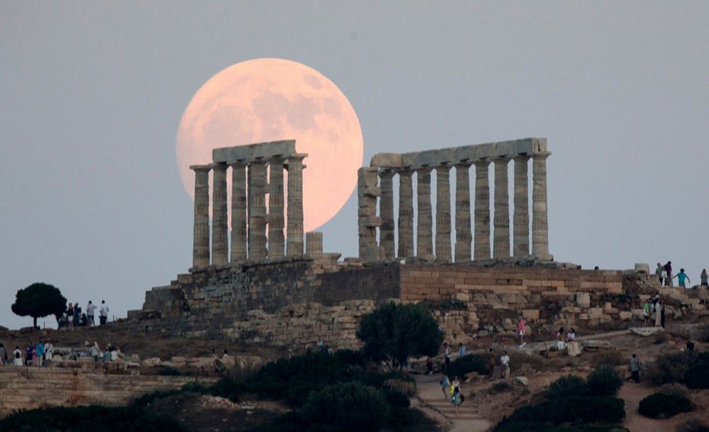 La luna piena sorge sopra l'Antico Tempio di Poseidone a Capo Sounion, a Sounion, in Grecia, il 2 luglio 2023