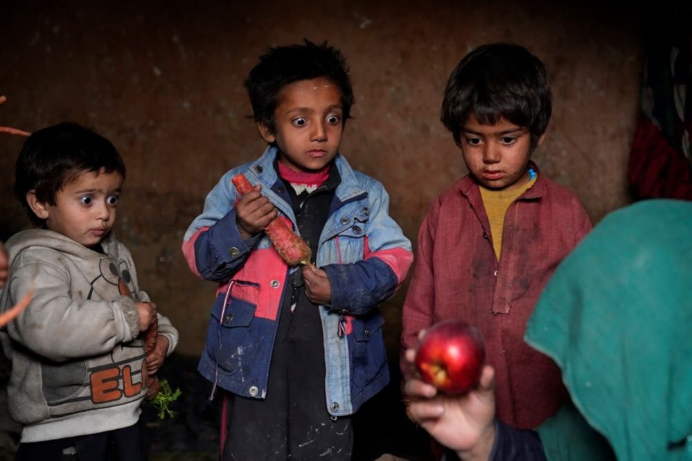 Children stare at an apple that their mother brought home after begging, 2 February 2023