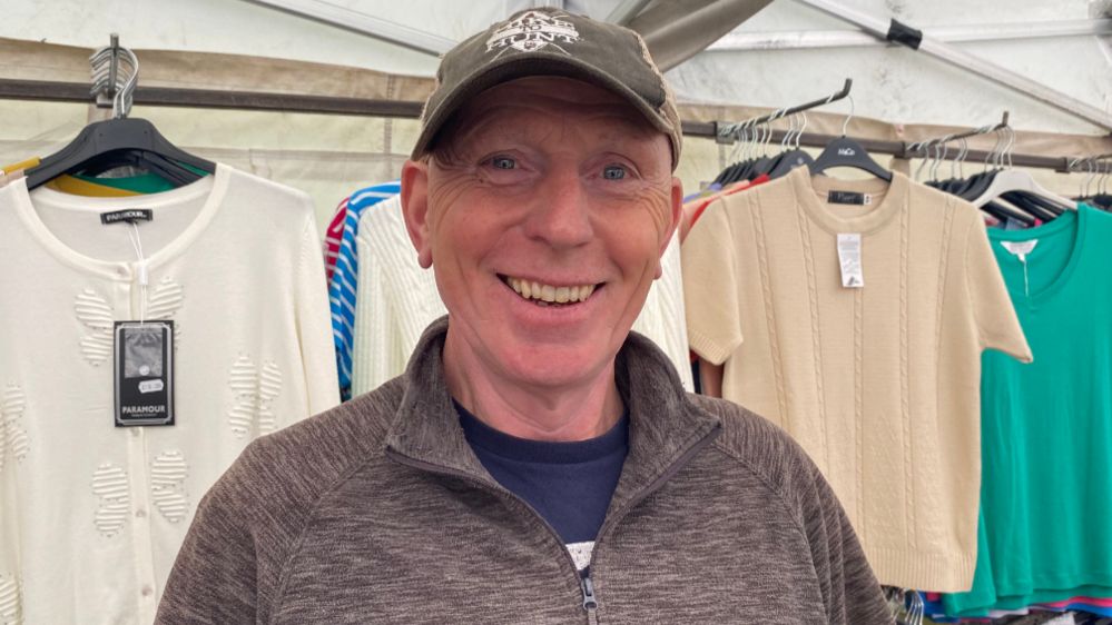 Simon Frankham standing in front of clothes at a market