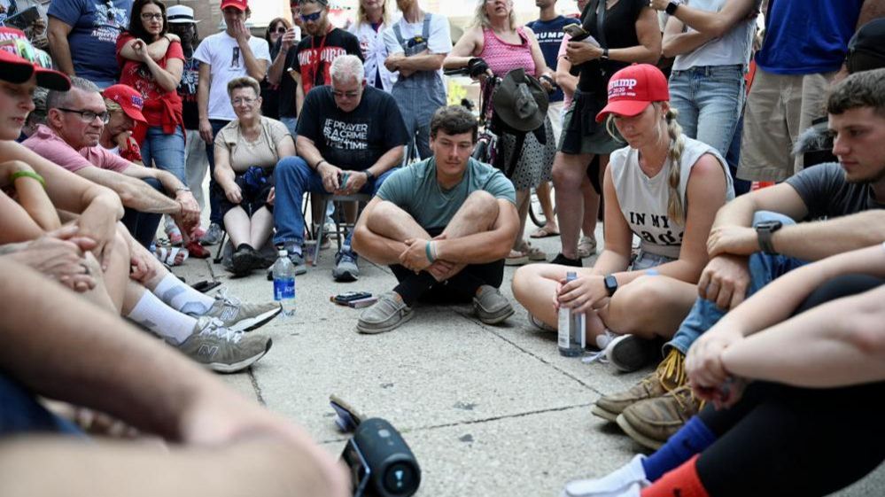 Trump supporters who could not get into the Grand Rapids rally listen outside on a speaker