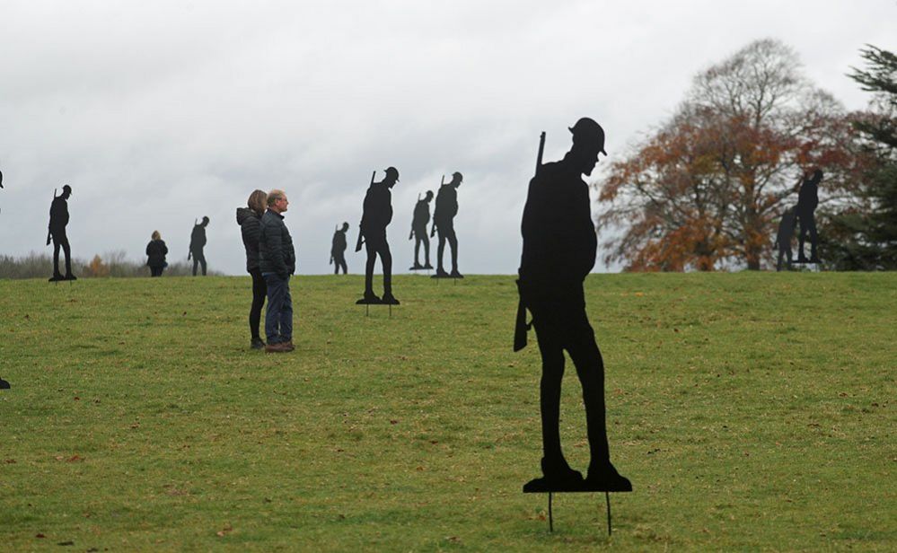 People observe a two minute silence amongst two hundred silhouettes of soldiers