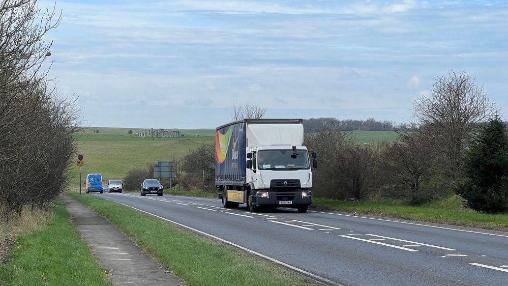 The A303 with cars and lorry and Stonehenge in the background