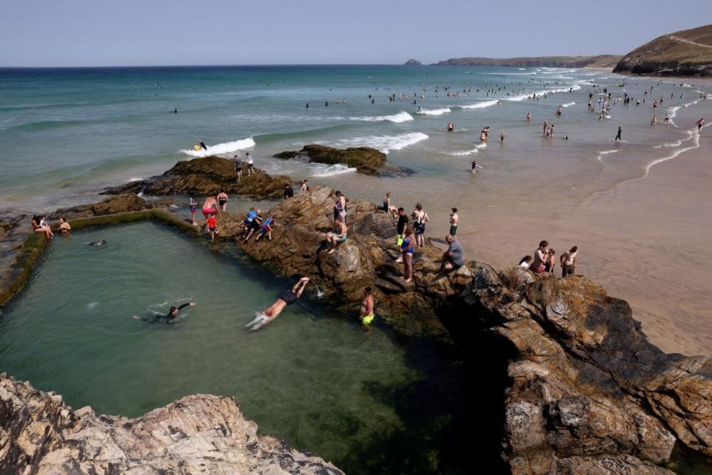 People swim in the tidal pool during hot weather at Perranporth Beach in Cornwall