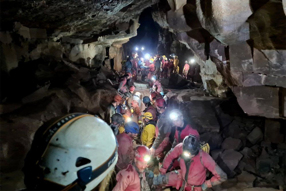 Rescue team carrying injured caver on a stretcher through a cave, 8 November 2021