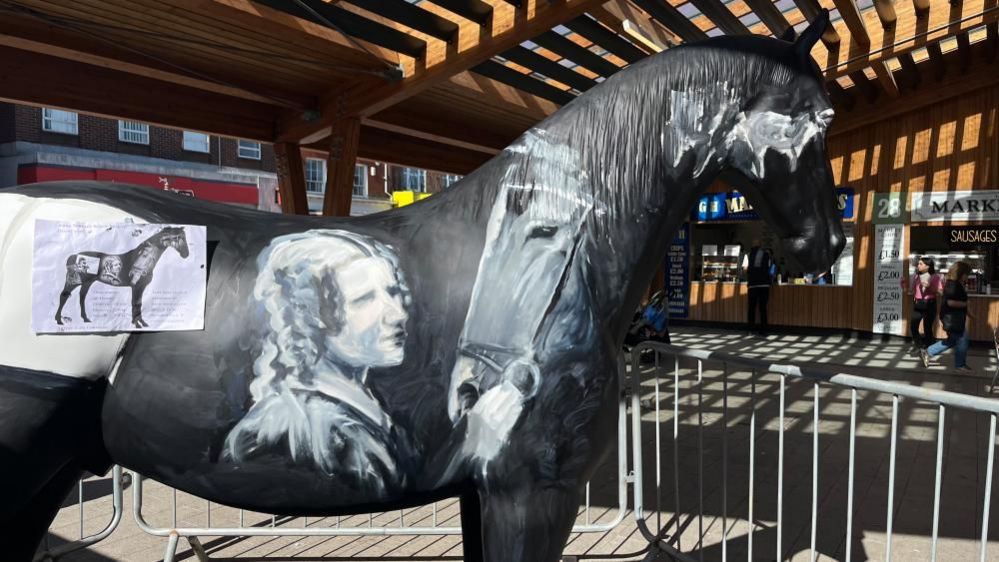 Anna Sewell and Black Beauty depicted on the side of a model of a horse, being created inside Great Yarmouth Market Hall