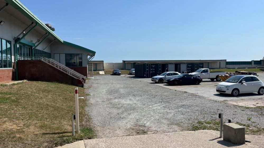 Disused roller skating rink being used for car parking and shipping container storage