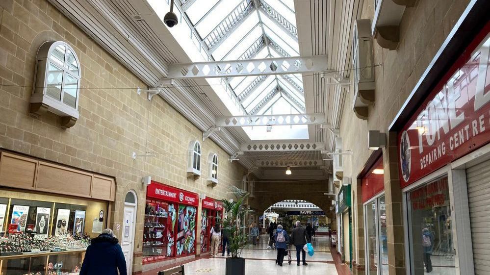 The inside of the under cover shopping centre with people walking down the middle