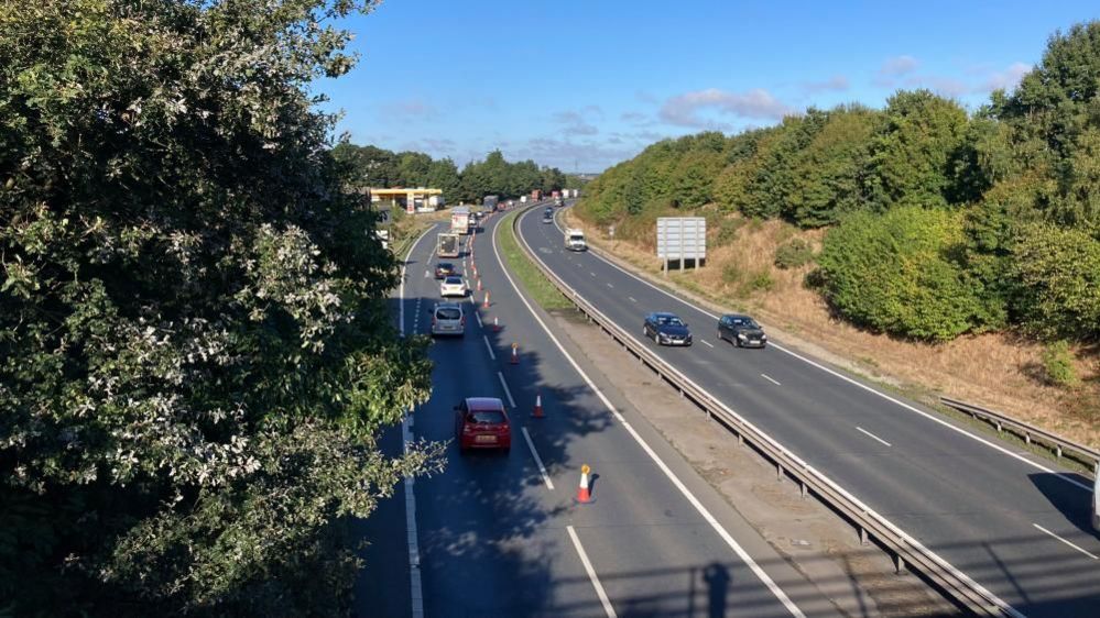 Cars driving on  the A14, with traffic cones out for a lane closure