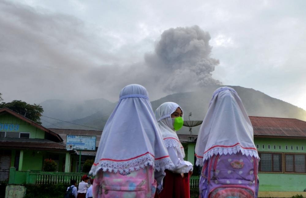 Students are seen at school in Nagari Batu Palano, Agam, as Mount Marapi volcano spews volcanic ash in the distance