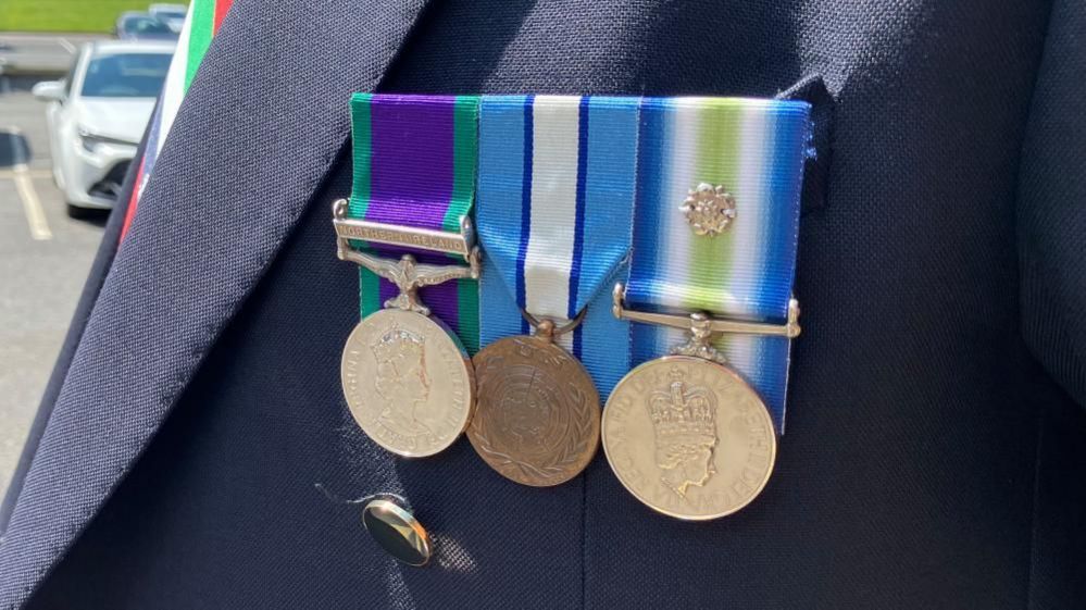 Close-up of three medals on a jacket 