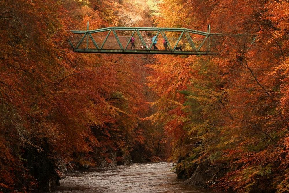 People cross a footbridge over the River Garry near Pitlochry, Scotland