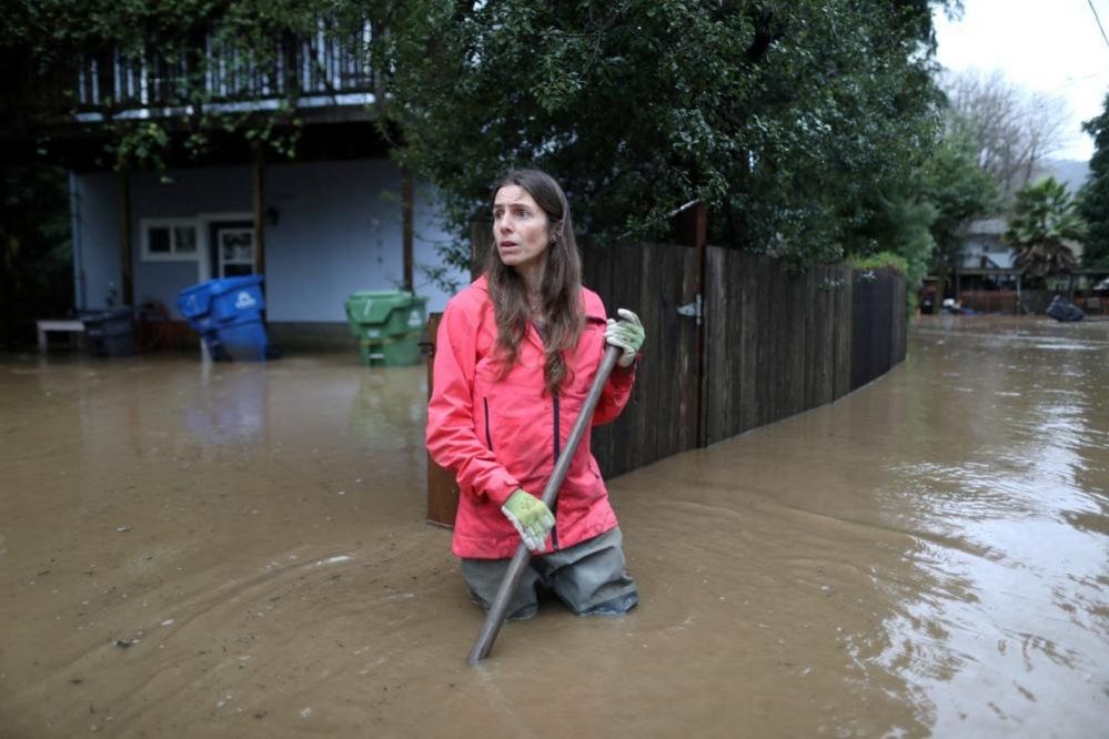 Melissa Foley clears debris as the San Lorenzo River rises