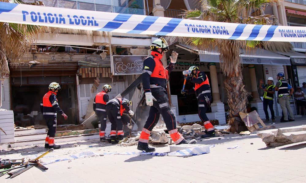 Firefighters gesture outside the site of the collapsed building in Palma on 24 May