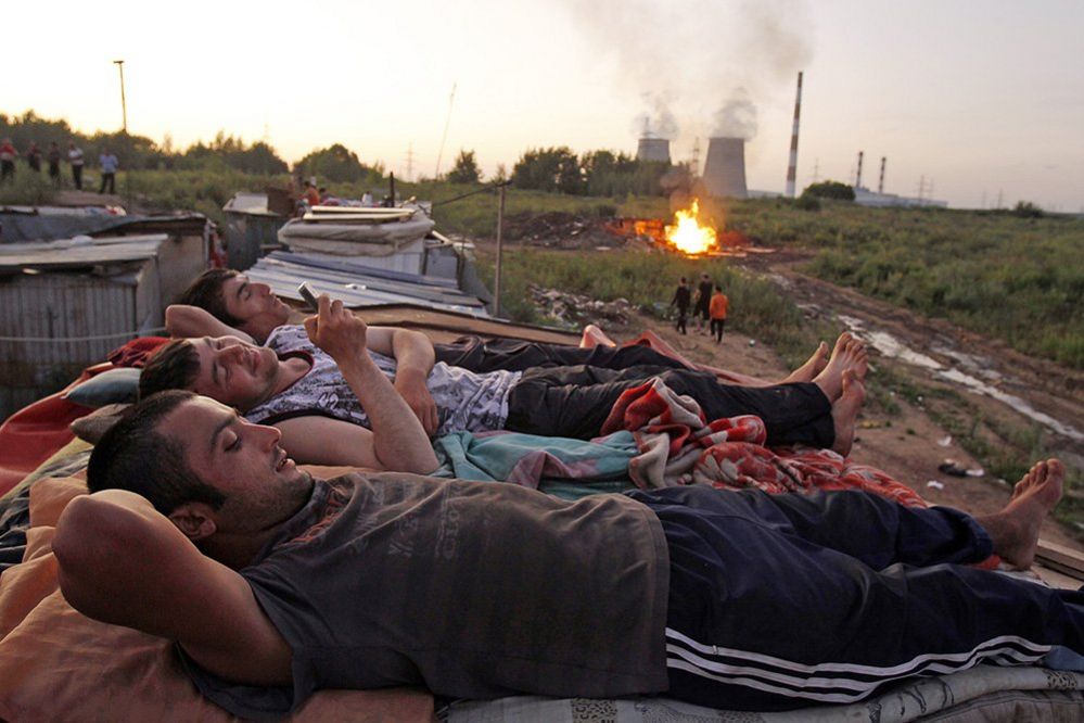 Migrants workers from Tajikistan relax on the roof of their shelter after working at local market outside Moscow, July 18 2011