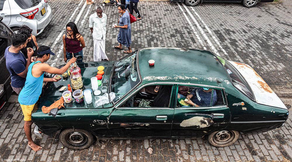 People enjoy street food on the bonnet of a car