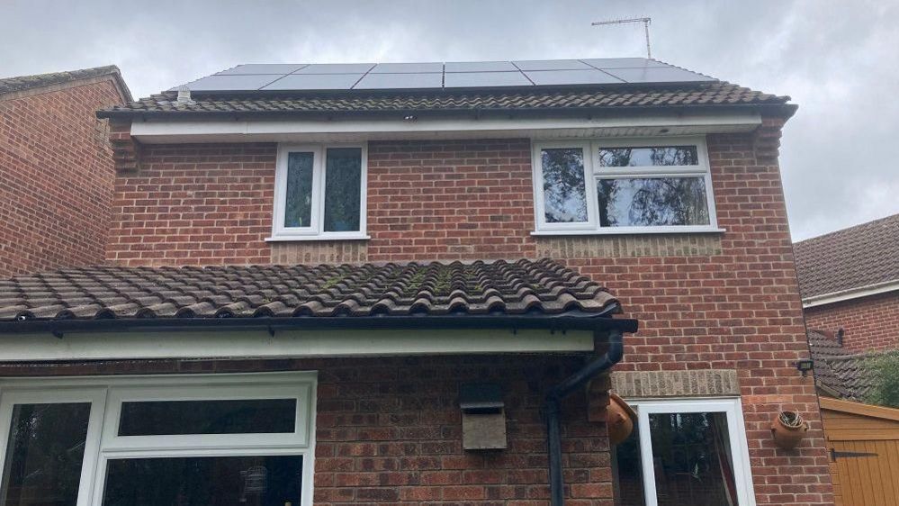 Back of a red brick house with solar panels on the roof