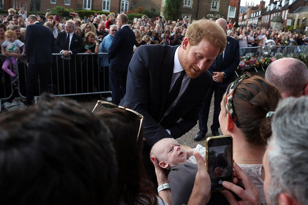Britain's Prince Harry greets people as he walk outside Windsor Castle