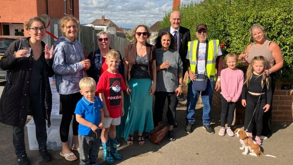 A small crowd of residents gather by the newly tarmacked alleyway