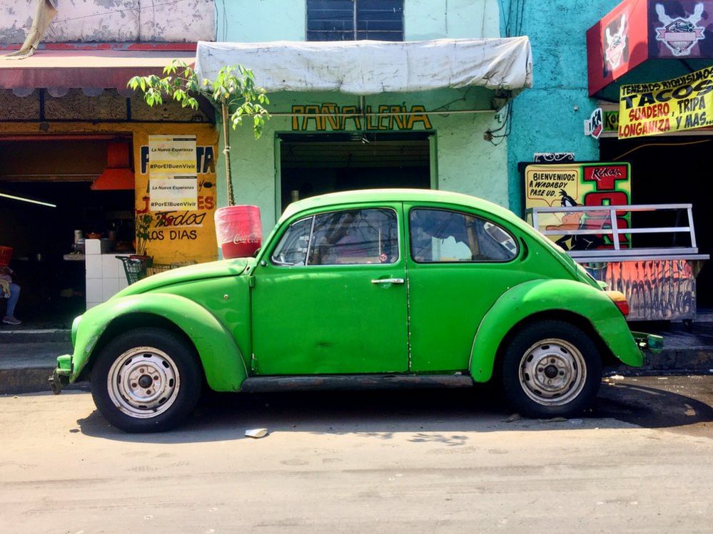 Green Volkswagen Beetle parked in front of some buildings