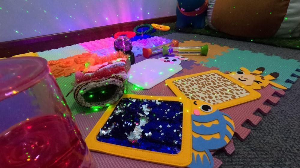 A jigsaw mat with colourful sensory items and a projector lighting up the area