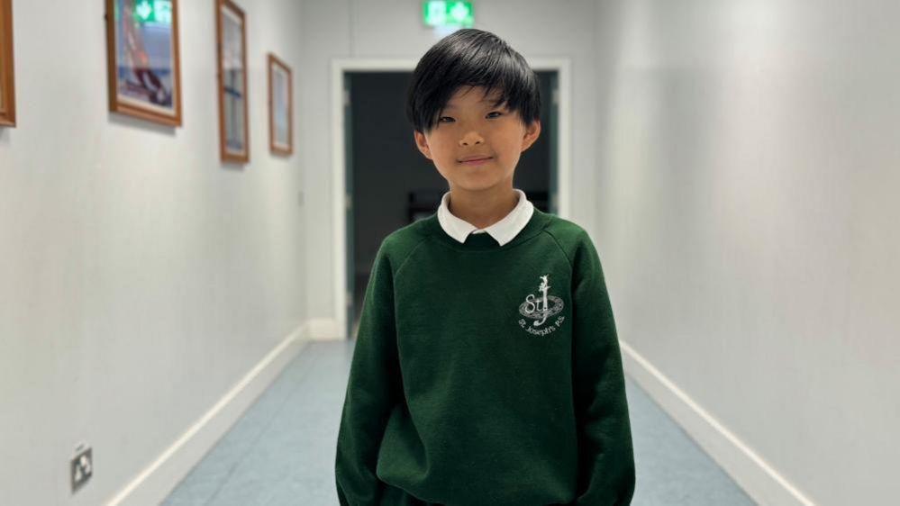 Little boy wearing green school uniform jumper