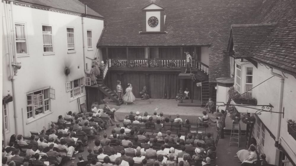 Black and white image of audience watching play