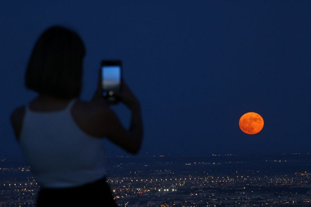 A woman takes a picture of the moon