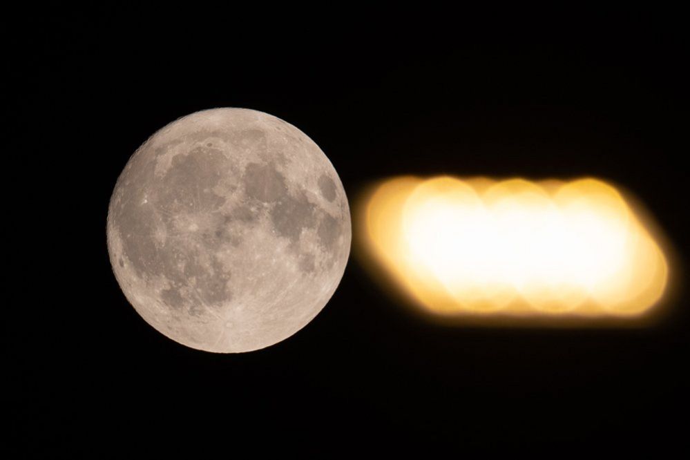 La superluna llena se ve junto a la luz de una farola en L'Aquila, Italia, el 2 de julio de 2023