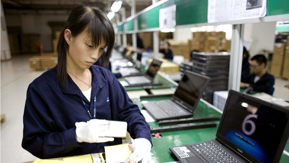 A woman assembles laptop computers