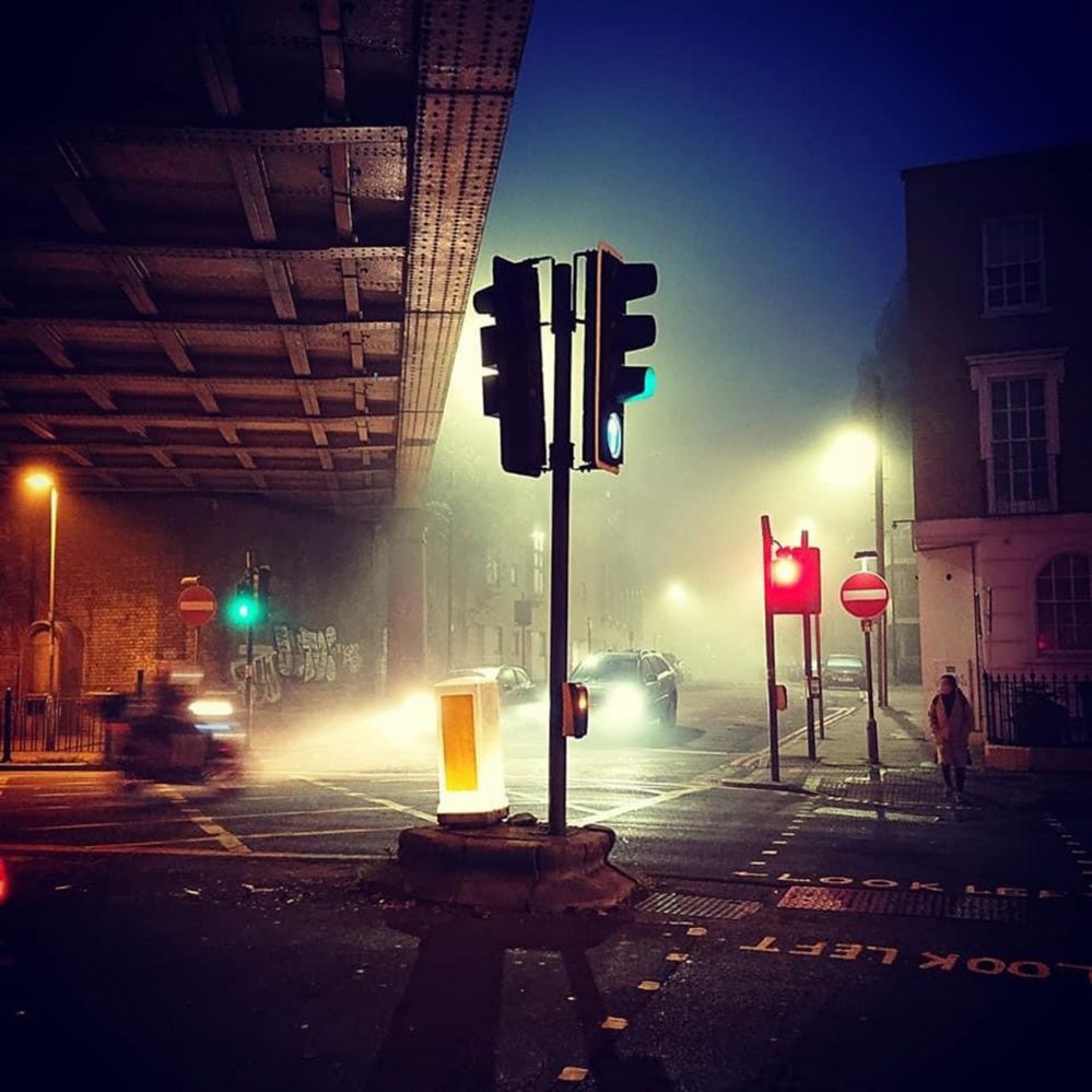 A view of traffic lights, vehicles, pedestrians and graffiti taken in Limehouse at dawn