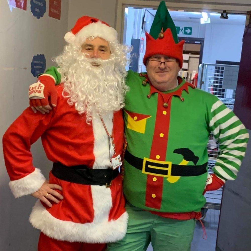 Postman Neil King in his Santa outfit alongside a colleague dressed as an elf