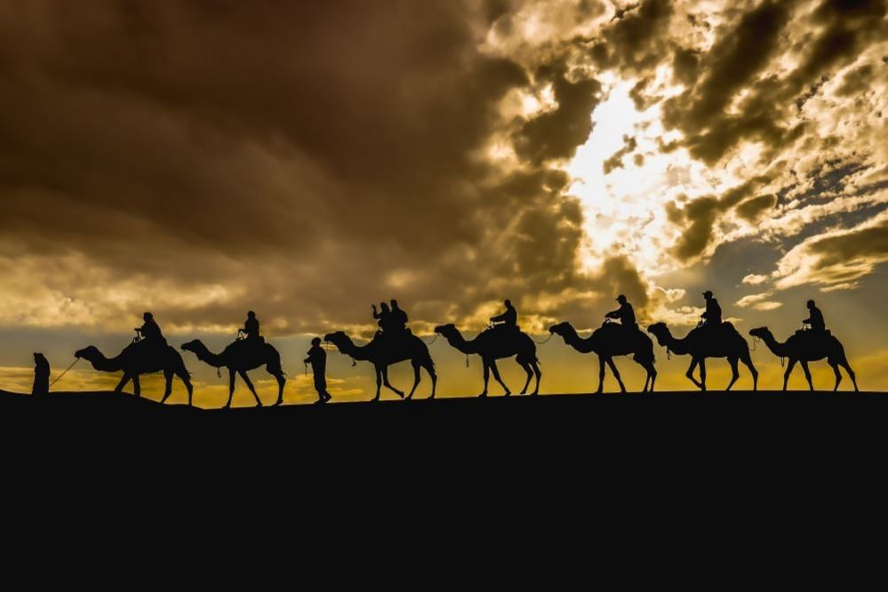 People ride camels in the desert