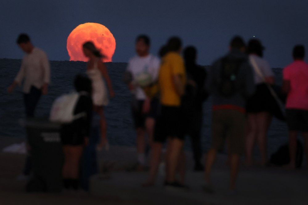 People gather along North Avenue Beach as a super blue moon rises on August 30, 2023 in Chicago, Illinois