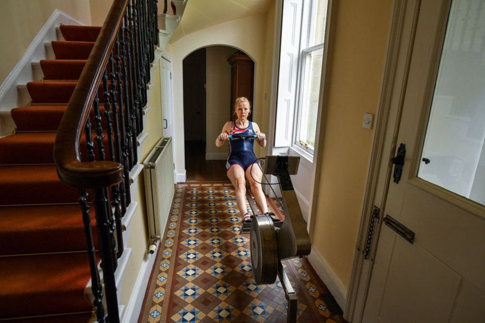 An athlete using a rowing machine in a hallway