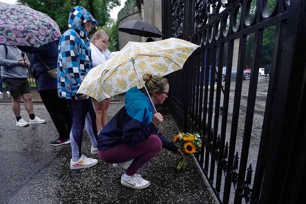 A member of the public lays flowers at the gates of the Palace of Holyroodhouse in Edinburgh